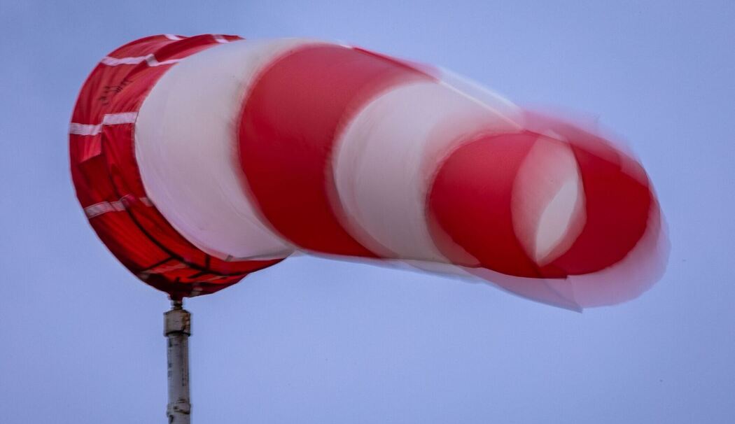 Windsack weht bei Regen und kräftigem Wind am Mast