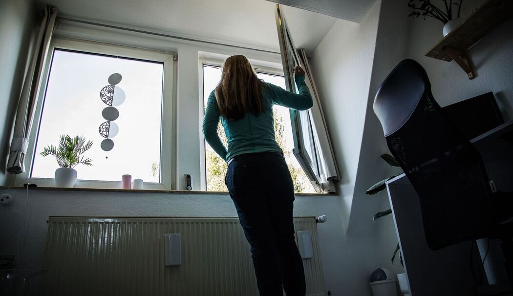 Frau öffnet zum Lüften ein Fenster Frau öffnet zum Lüften ein Fenster