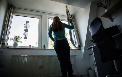 Frau öffnet zum Lüften ein Fenster