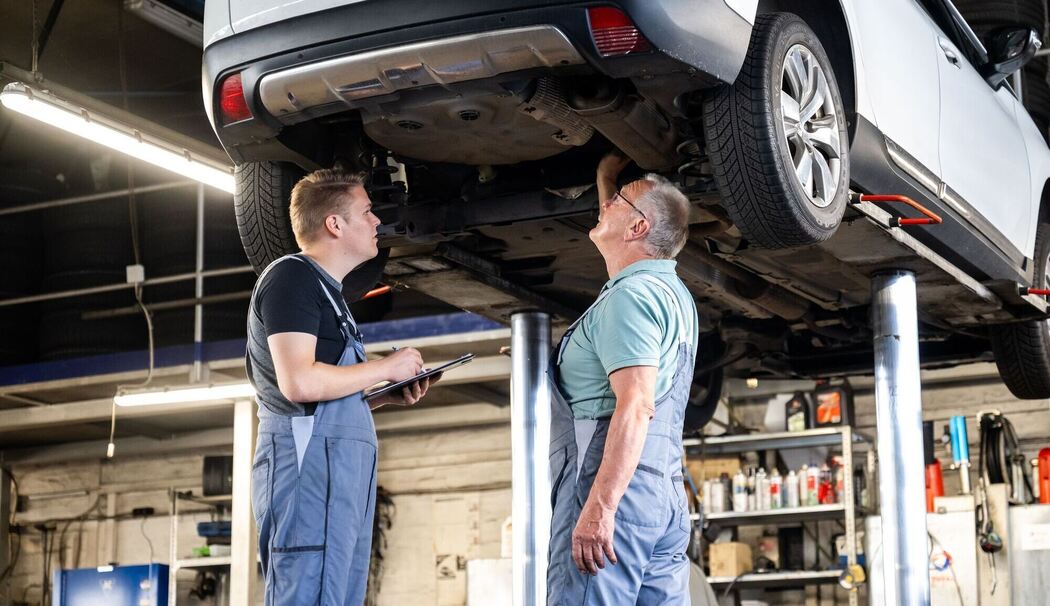 Zwei Männer arbeiten gemeinsam in einer Autowerkstatt Zwei Männer arbeiten gemeinsam in einer Autowerkstatt