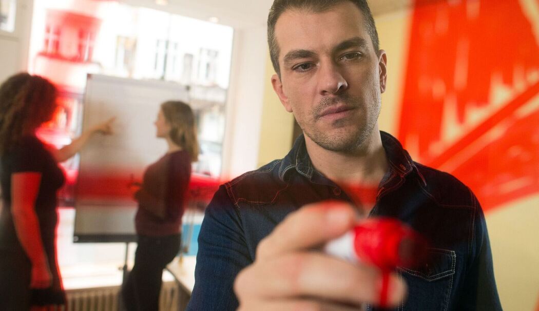 Mann malt zur Visualisierung einen Kreis an eine Plexiglasscheibe Mann malt zur Visualisierung einen Kreis an eine Plexiglasscheibe