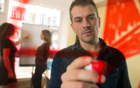 Mann malt zur Visualisierung einen Kreis an eine Plexiglasscheibe