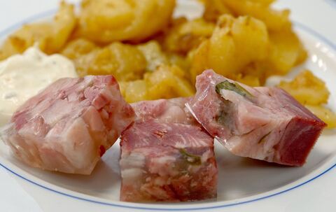 Sülze liegt auf einem Teller mit Bratkartoffeln