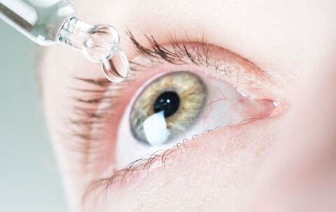 Frau benutzt befeuchtende Augentropfen