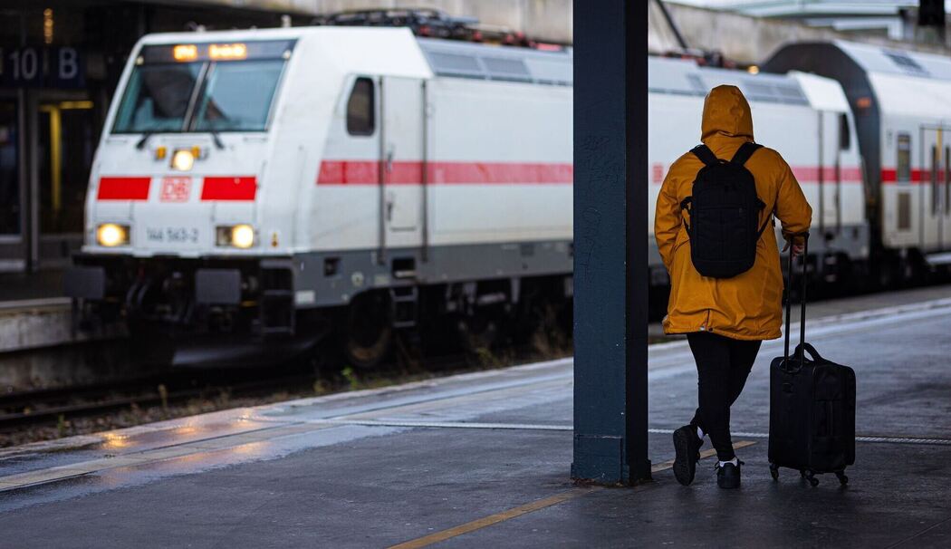 Reisende wartet bei Regen und Herbststurm am Bahnhof auf den Zug Reisende wartet bei Regen und Herbststurm am Bahnhof auf den Zug