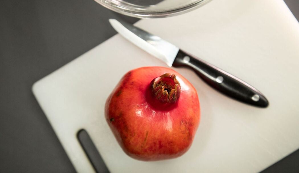 Granatapfel liegt neben einem Messer auf einem Tisch Granatapfel liegt neben einem Messer auf einem Tisch