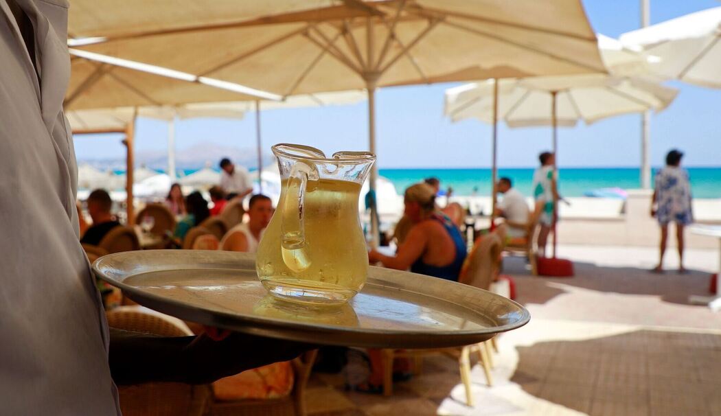 Kellner serviert am Strand einen Wein Kellner serviert am Strand einen Wein