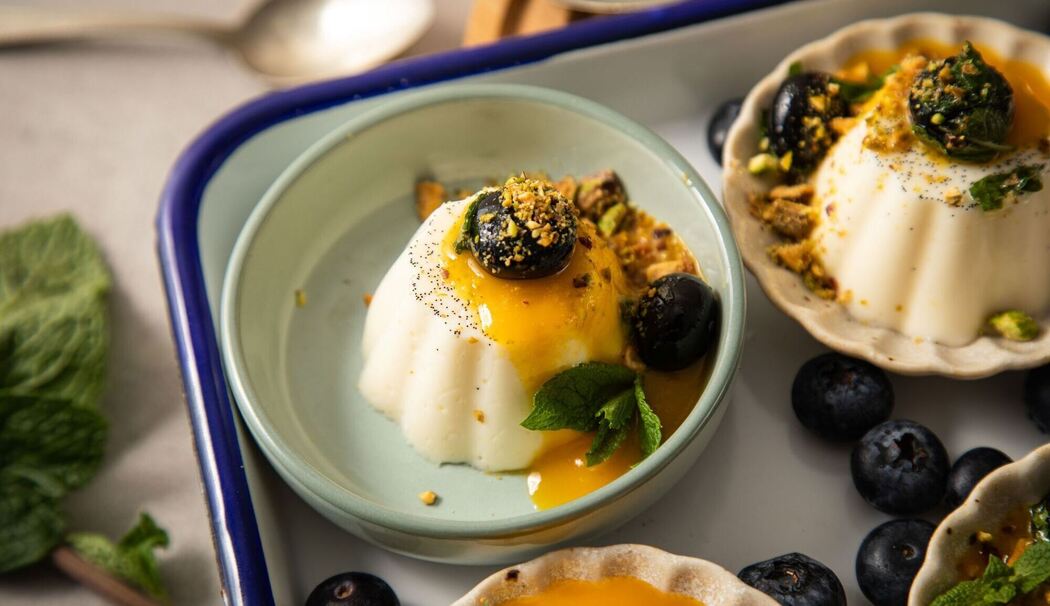 Vanille Panna Cotto mit Mangosoße, Blaubeeren, Minze, Pistazien Vanille Panna Cotto mit Mangosoße, Blaubeeren, Minze, Pistazien