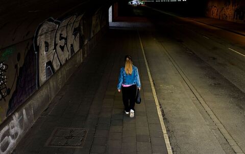 Frau läuft am Abend durch einen Tunnel mit geringer Beleuchtung
