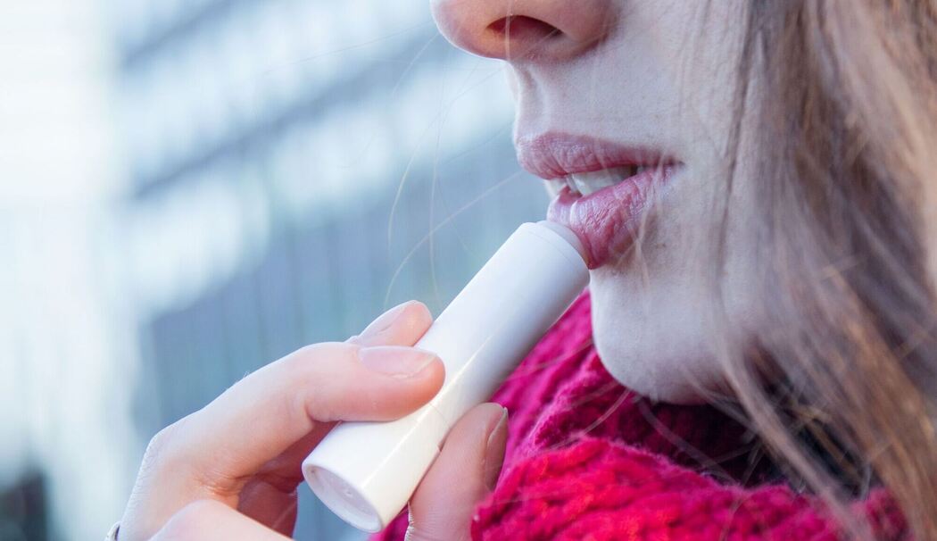 Frau trägt eine Lippenpflege auf Frau trägt eine Lippenpflege auf