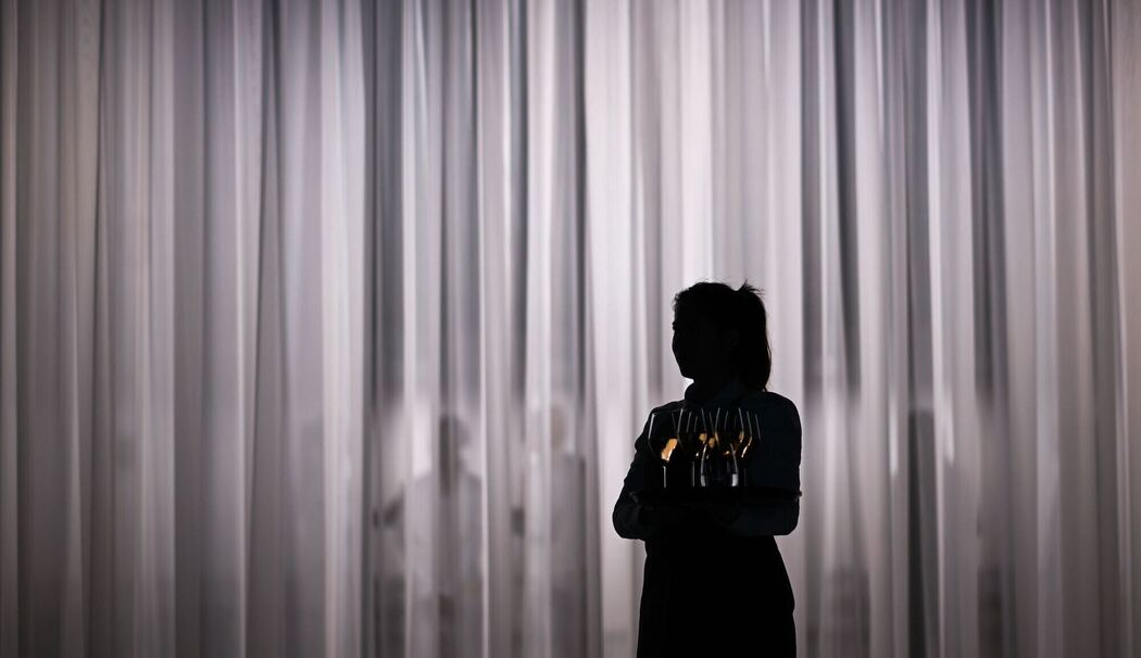 Eine Servicemitarbeiterin steht vor einem hellen Vorhang Eine Servicemitarbeiterin steht vor einem hellen Vorhang