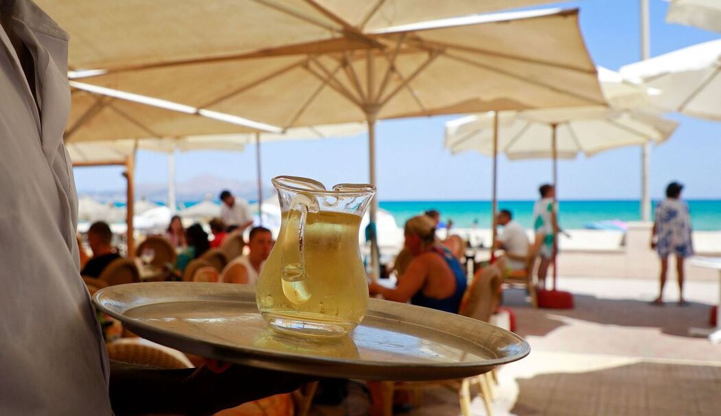 Ein Kellner serviert an einem mallorquinischen Strand einen Wein