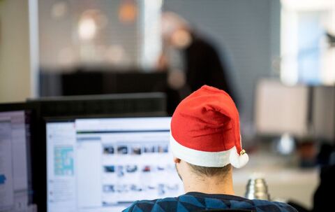 Ein Mann sitzt mit Weihnachtsmütze im Büro