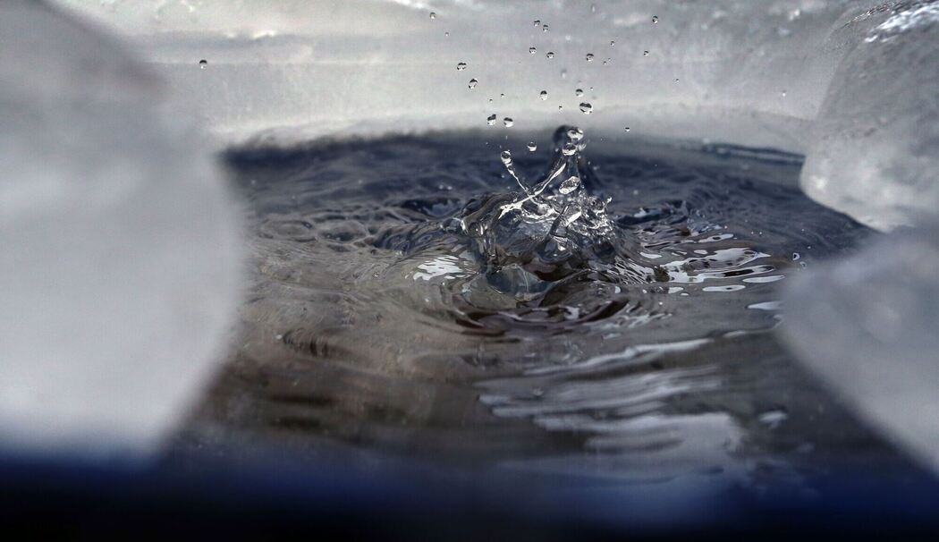 Wasser tropft in eine von Eis umgebene Regentonne