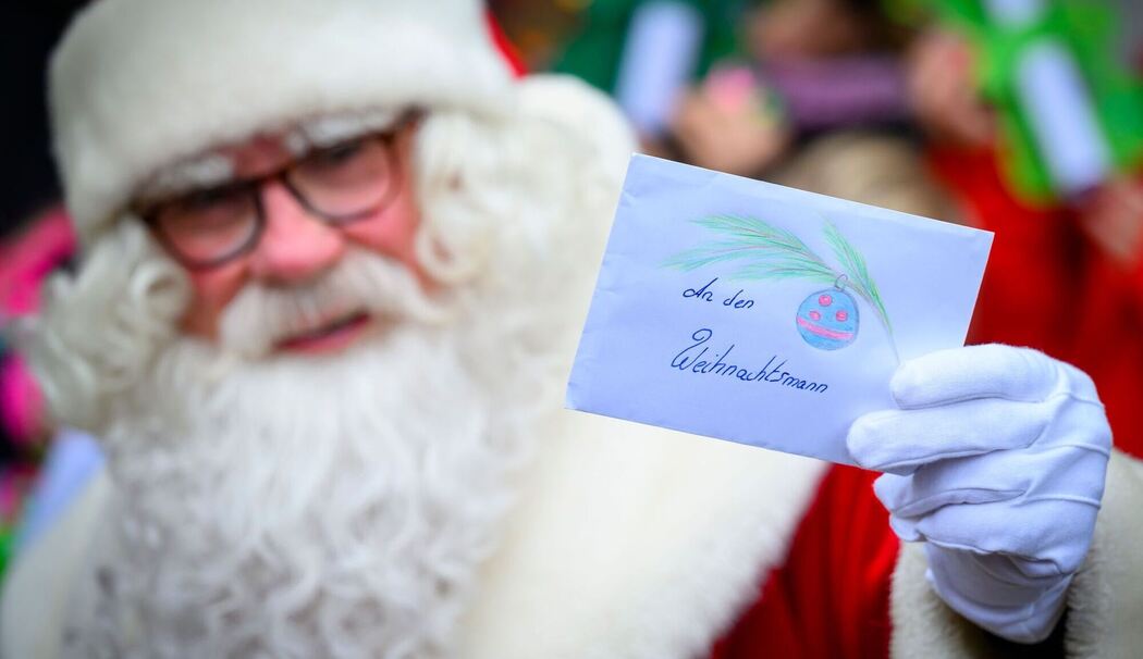 Weihnachtsmann hält Weihnachtspost hoch