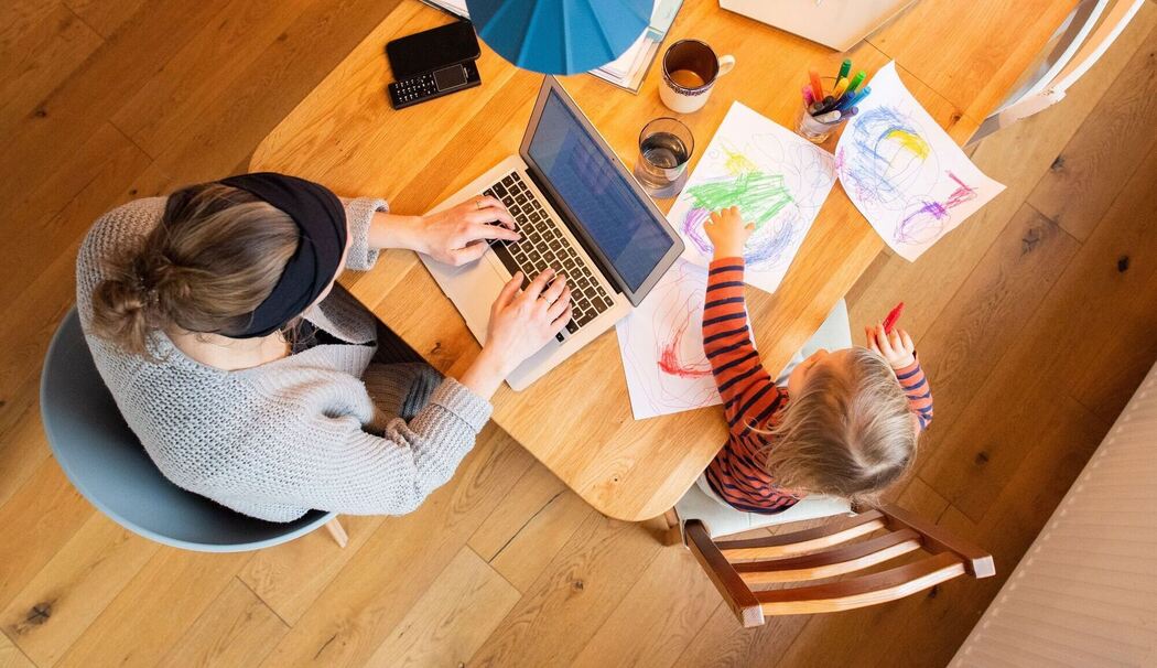 Eine Frau arbeitetneben ihrem Kind am Laptop