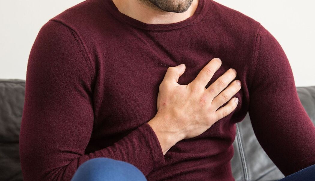 Ein Mann hält sich vor Brustschmerzen die Brust Ein Mann hält sich vor Brustschmerzen die Brust