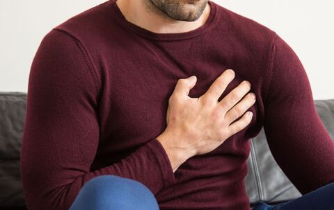 Ein Mann hält sich vor Brustschmerzen die Brust