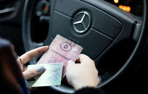 Eine Frau hält einen Papier-Führerschein und neuen Führerschein