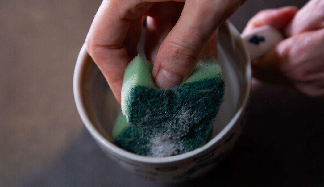 Tasse wird mit einem Schwamm gereinigt Tasse wird mit einem Schwamm gereinigt