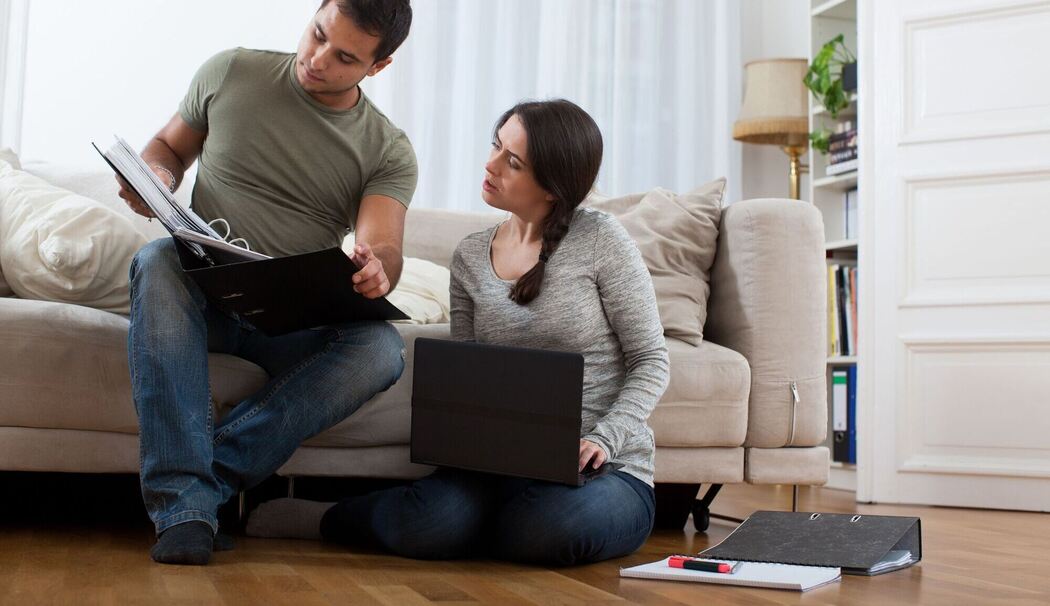 Ein Paar sieht gemeinsam in Unterlagen Ein Paar sieht gemeinsam in Unterlagen