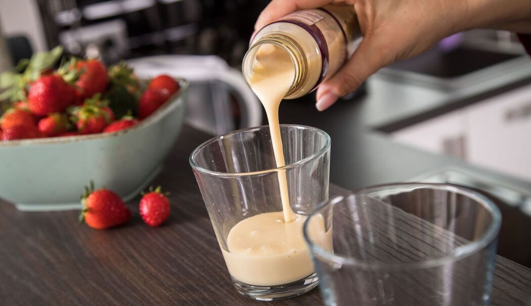 Eine Frau gießt ein Fertig-Getränk in ein Glas Eine Frau gießt ein Fertig-Getränk in ein Glas