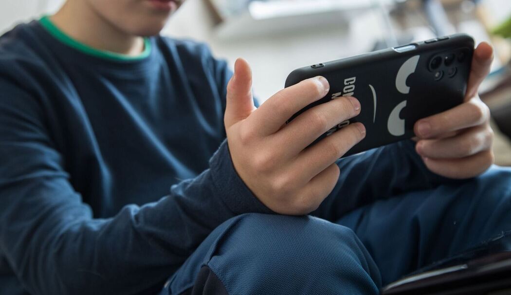 Junge schaut auf sein Smartphone Junge schaut auf sein Smartphone