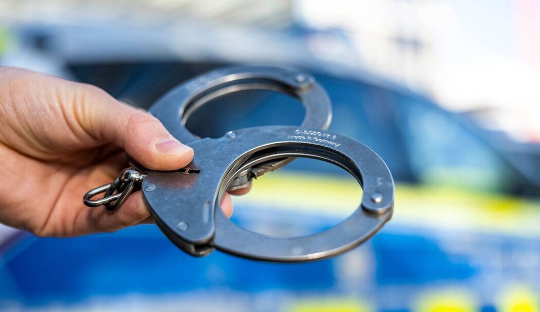 Handschellen vor Polizeiwagen - Symbolbild Handschellen vor Polizeiwagen - Symbolbild
