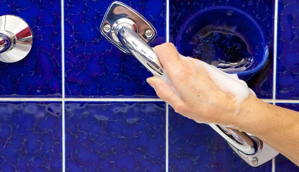 Eine Hand greift einen Haltegriff im Bad Eine Hand greift einen Haltegriff im Bad