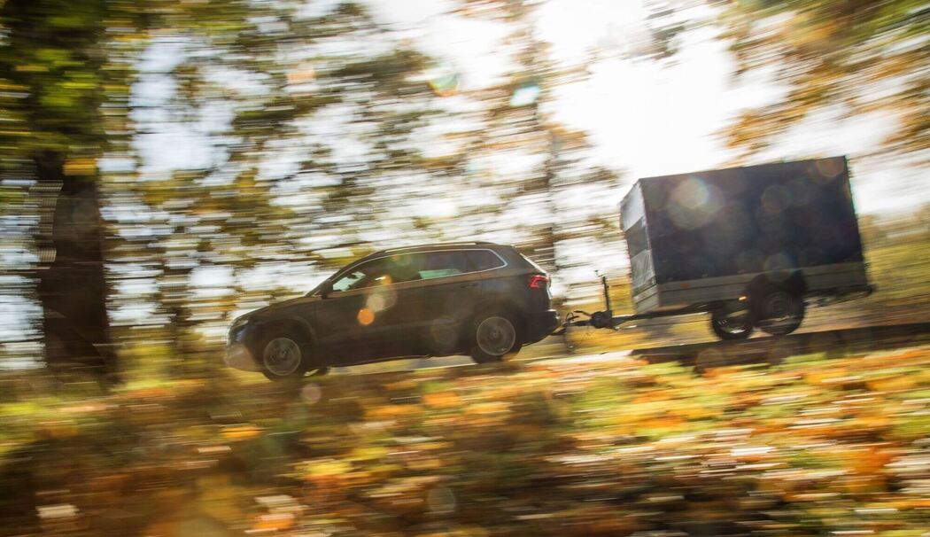 Ein Auto mit Anhänger fährt die Straße entlang Ein Auto mit Anhänger fährt die Straße entlang