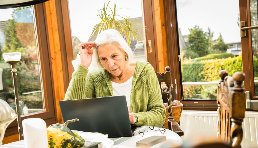 Eine Seniorin arbeitet an ihrem Laptop