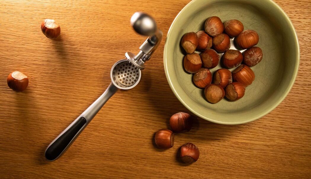 Haselnüsse liegen neben einer Knoblauchpresse Haselnüsse liegen neben einer Knoblauchpresse