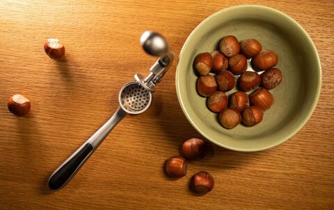 Haselnüsse liegen neben einer Knoblauchpresse