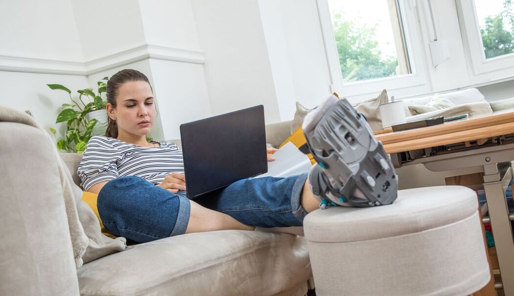 Eine Frau mit Fuß im Gips auf dem Sofa