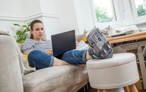 Eine Frau mit Fuß im Gips auf dem Sofa