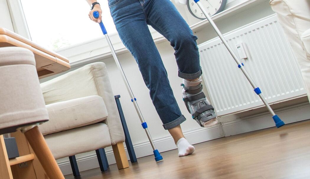 Eine Frau mit Krücken und Fuß mit Gips