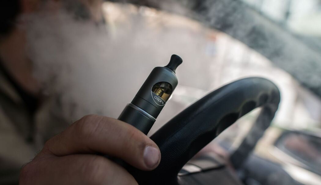 Ein Mann raucht eine E-Zigarette im Auto