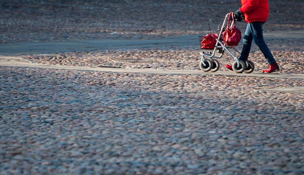 Frau geht mit ihrem Rollator über den Marktplatz von Lüneburg Frau geht mit ihrem Rollator über den Marktplatz von Lüneburg