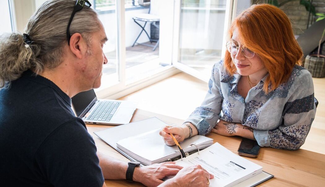 Frau und Mann sitzen vor Unterlagen