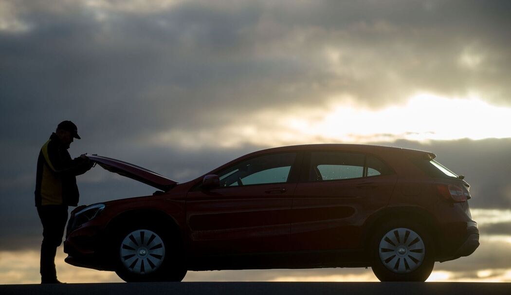 Mann öffnet die Motohaube eines Autos