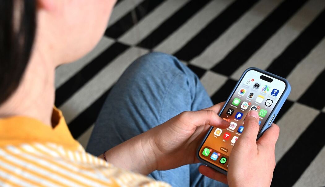 Eine Jugendliche sitzt am Smartphone (Archivbild)