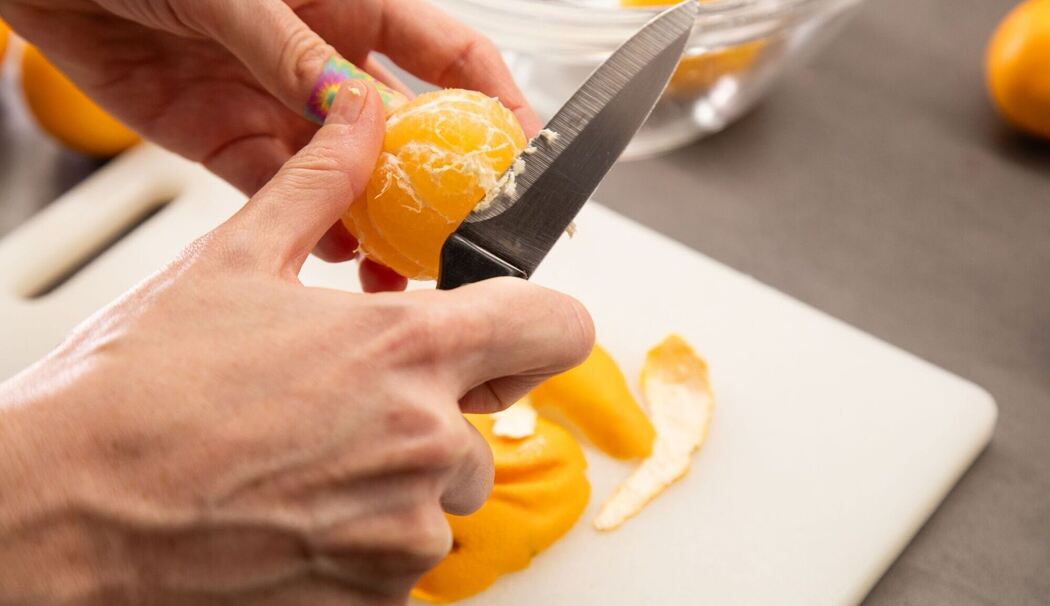 Clementinen werden mit einem Messer von den weißen Fäden befreit