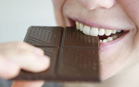 Frau beißt in ein Stück Schokolade
