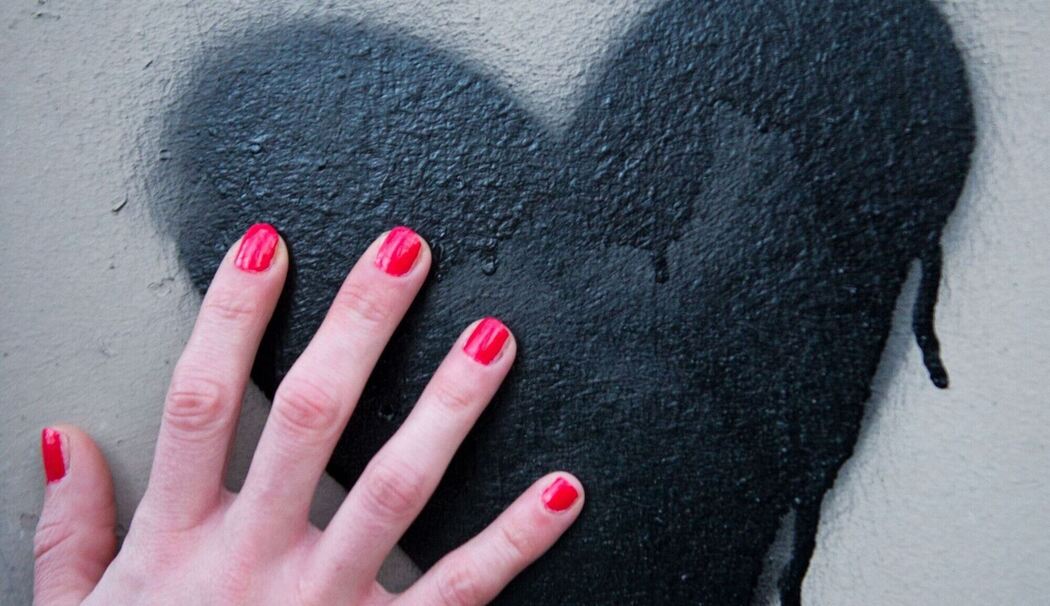 Frauenhand berührt ein auf die Wand gesprühtes Herz