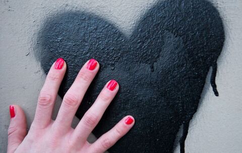 Frauenhand berührt ein auf die Wand gesprühtes Herz