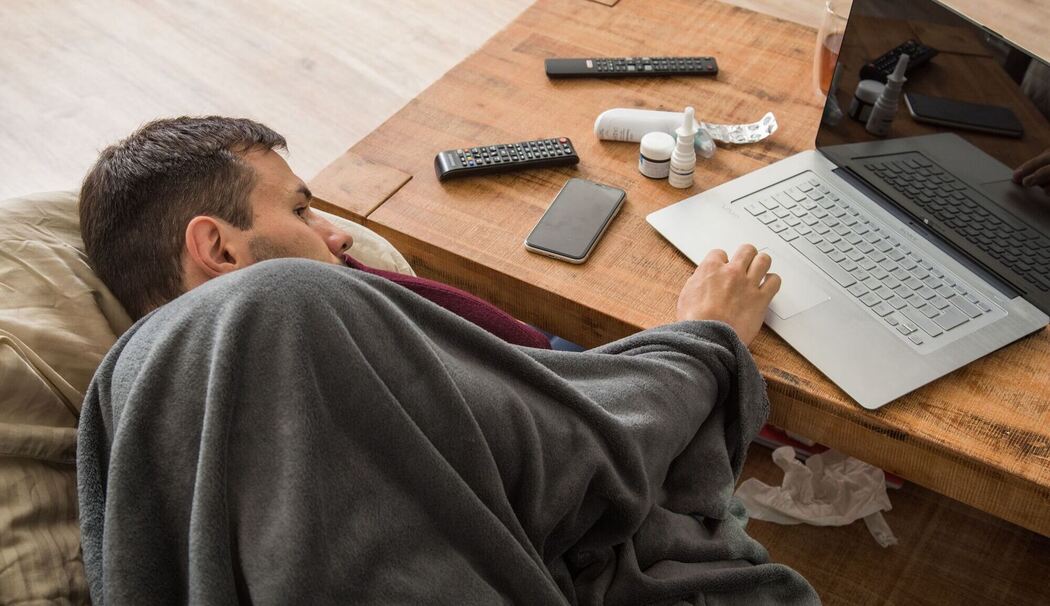 Ein Mann mit Erkltung bedient ein Laptop Ein Mann mit Erkltung bedient ein Laptop