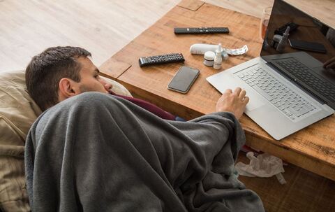 Ein Mann mit Erkltung bedient ein Laptop