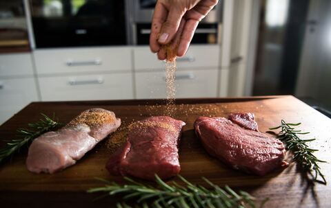 Eine Perosn würzt Fleisch