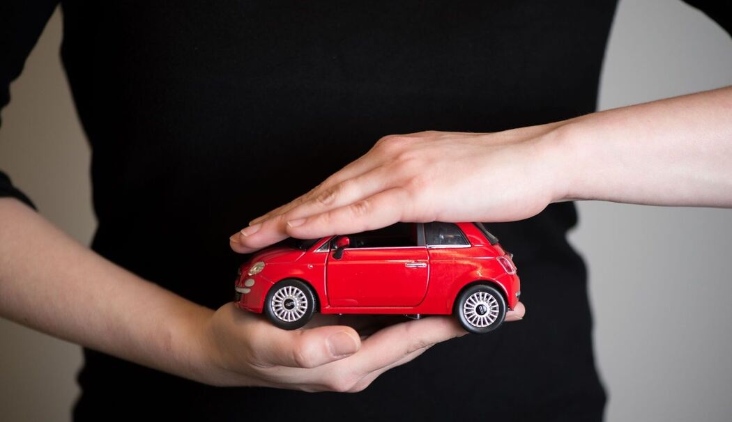 Eine Frau hält ein Modellauto in den Händen
