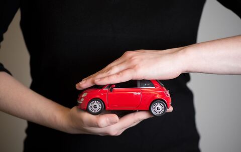 Eine Frau hält ein Modellauto in den Händen